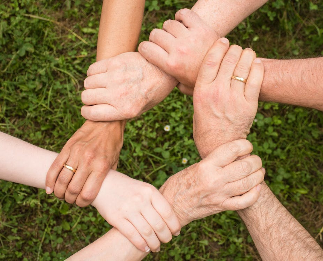 People holding hands to emphasize the role of social support in addiction recovery.